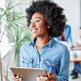 Woman smiling while holding tablet in office