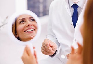 Woman smiling in reflection of handheld mirror
