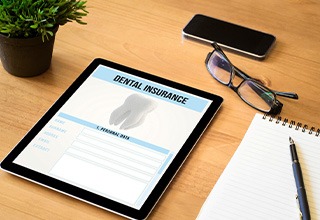 Dental insurance form on tablet next to desk supplies