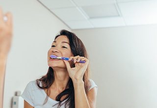 Woman brushing her teeth in bathroom