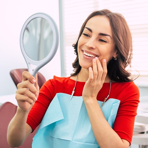 Pleased woman looking at her smile after dental treatment