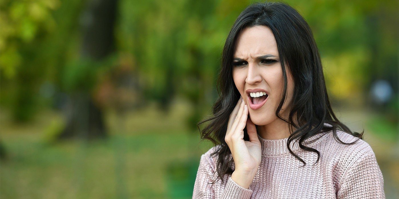 Woman with a toothache in Weatherford holding her cheek