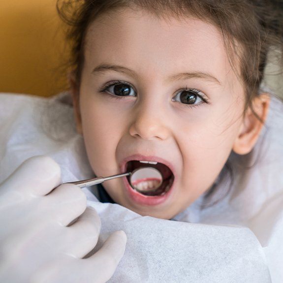 Dentist checking child's smile after tooth colored filling placement