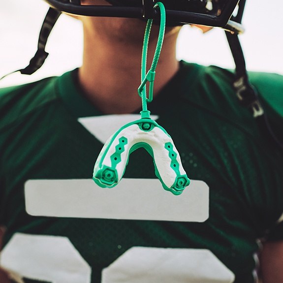 Young athlete with mouthguard hanging from his helmet