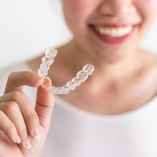 smiling person holding clear aligners in Weatherford