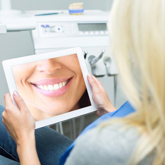 Woman looking at virtual smile design on tablet computer