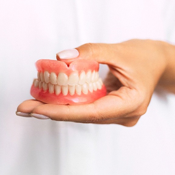 Dentist in Weatherford holding dentures