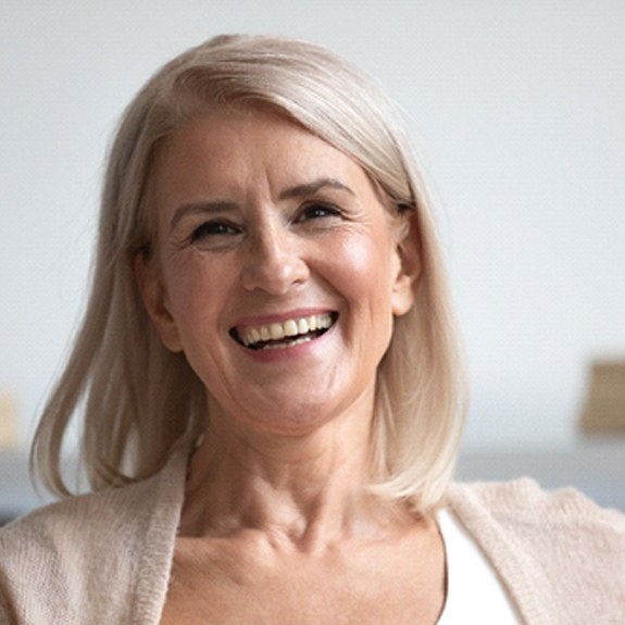 Woman on couch smiling with dentures in Weatherford, TX