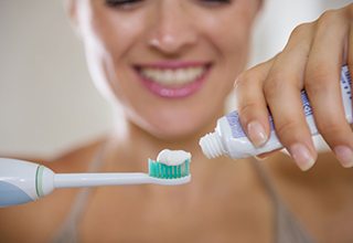 woman putting toothpaste on a toothbrush