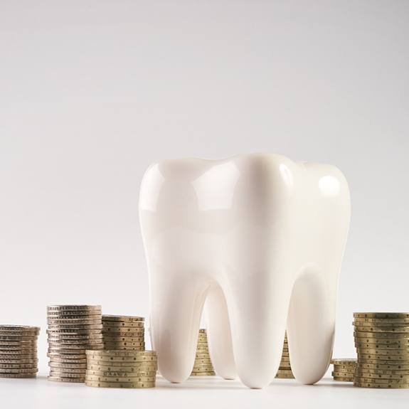 Tooth model surrounded by stacks of coins