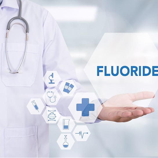 A doctor standing next to symbols that refer to fluoride