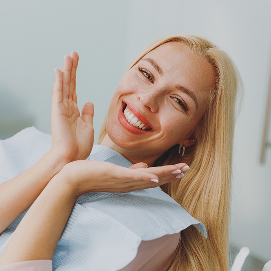 A smiling woman in a dentist’s office spreading her hands