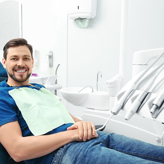 Male dental patient sitting in treatment chair with hands folded