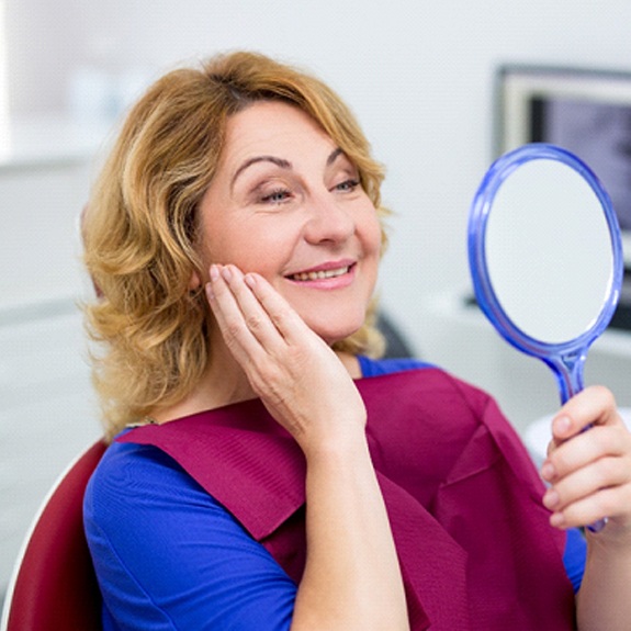 Woman admiring her new implant denture in Weatherford