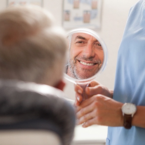 Dentist showing male patient smile after placing dental implants in Weatherford, TX