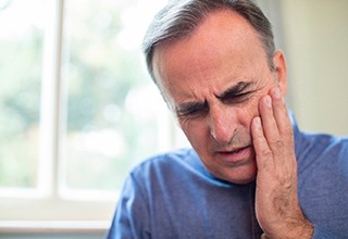 Man rubbing jaw while recovering from dental implants in Weatherford, TX