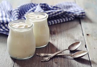 Two cups of yogurt with two spoons nearby