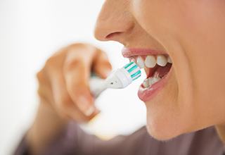 Woman with dental implants in Weatherford, TX brushing her teeth