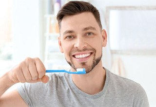 Man in grey shirt about to brush his teeth