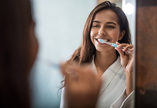 Woman in front of mirror, brushing her teeth before bed