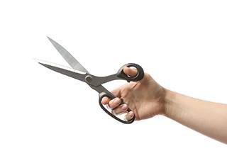 Hand holding scissors against white background, ready to open package