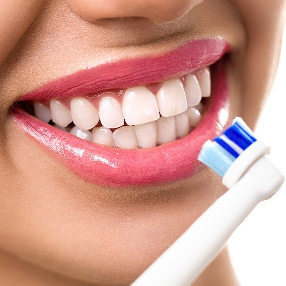Patient using electric tooth brush during at home oral hygiene routine