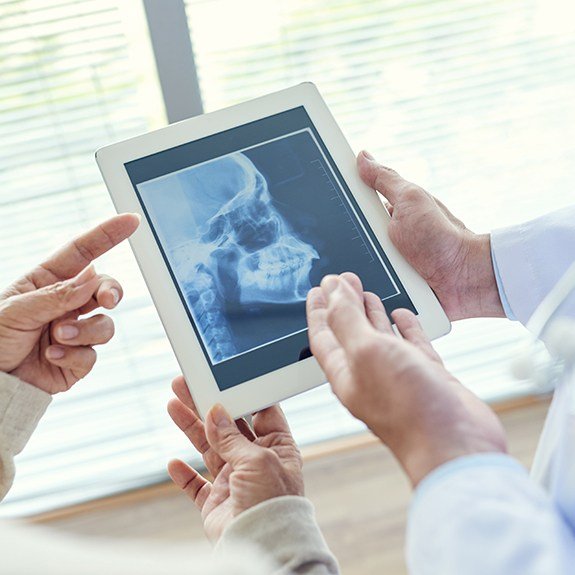 Dentists reviewing digital x-ray of jaw and skull bone before T M J therapy