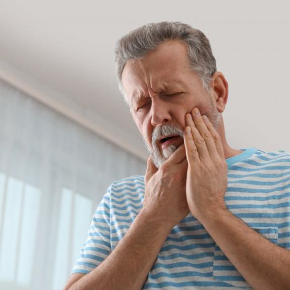 a man holding his jaw due to dental implant failure