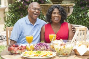 couple with dental implants enjoying summer foods outside 