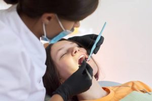 Dentist performing treatment on sedated female patient
