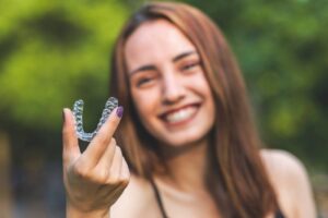 Young woman holding clear aligner.