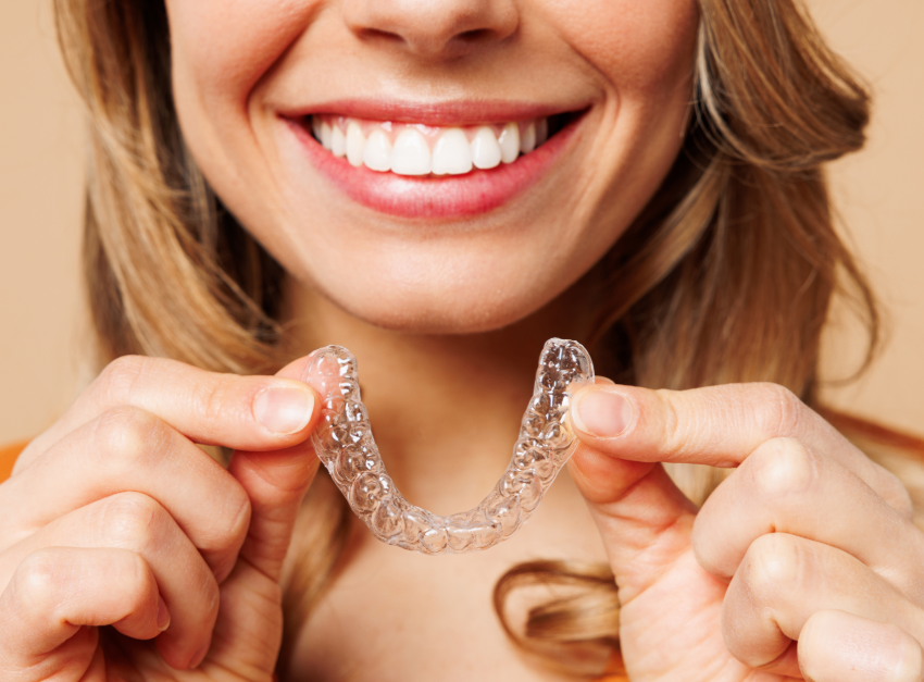Woman smiling and holding clear aligner