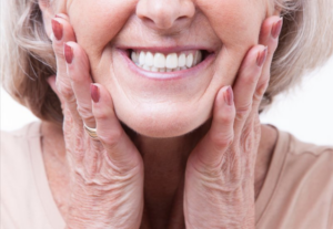Close up of a woman smiling and pressing her hands to her cheeks